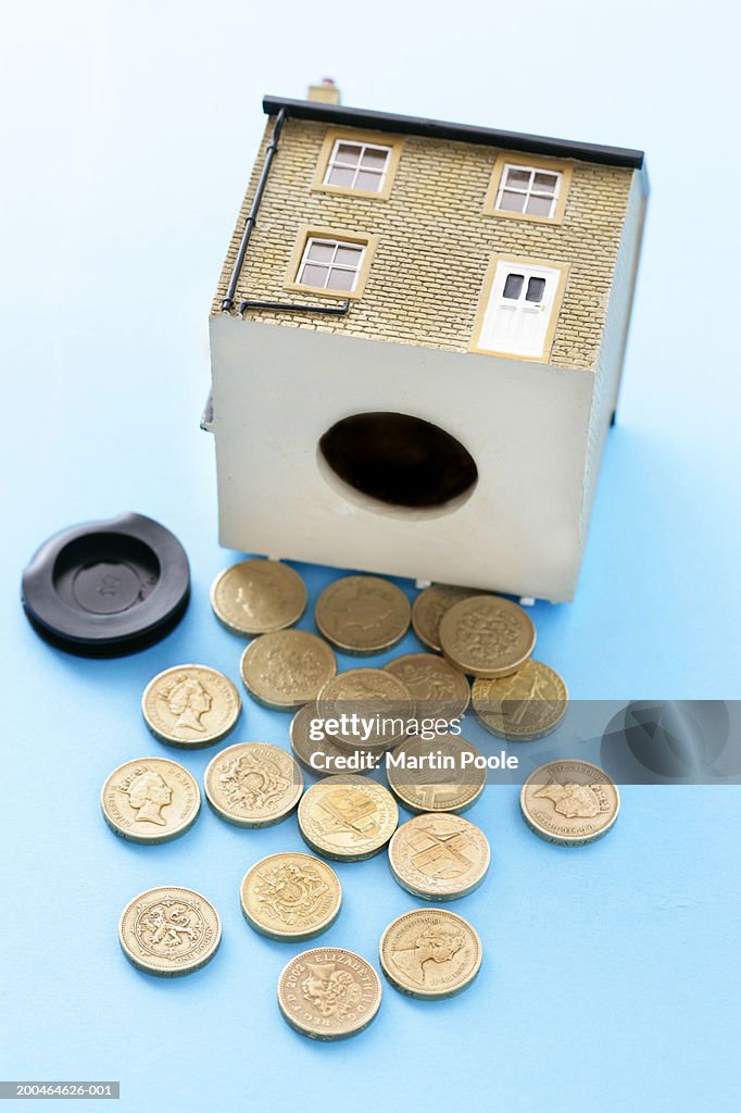 One pound coins tipped out from money box in form of house