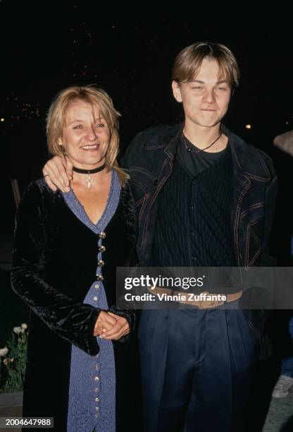 American actor Leonardo DiCaprio, wearing a black crew neck top beneath a black jacket with red stitching, and his mother, Irmelin Indenbirken, who...