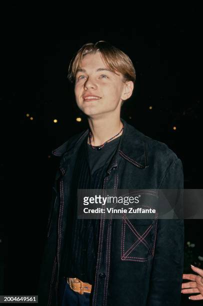 American actor Leonardo DiCaprio, wearing a black crew neck top beneath a black jacket with red stitching, attends the Hollywood premiere of 'What's...