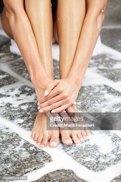 woman sitting in shower, low section, close-up - womens beautiful feet stock-fotos und bilder