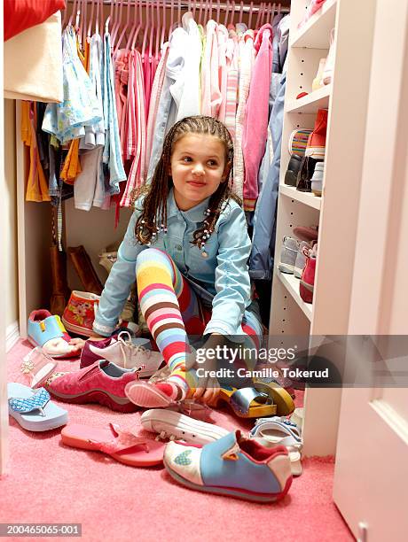 girl (6-8) putting on shoes in closet, smiling, close-up - shoes closet ストックフォトと画像