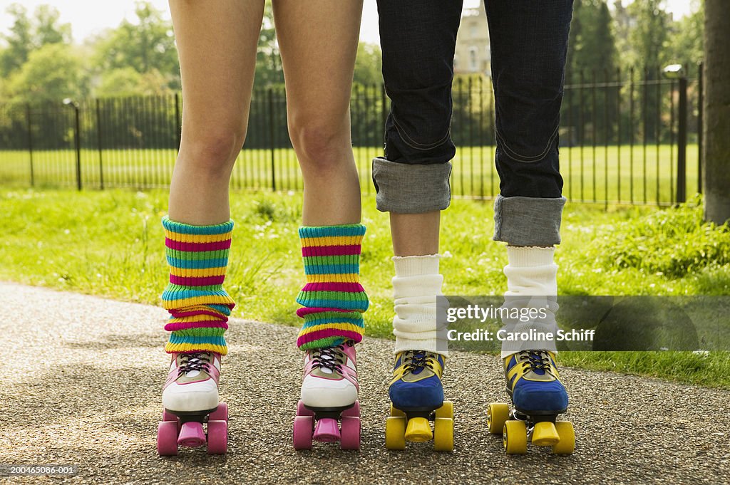 Two young women wearing roller skates, low section