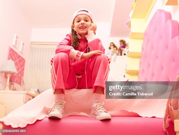 girl (6-8) listening to music in bedroom, portrait, low angle view - pink hat stock pictures, royalty-free photos & images