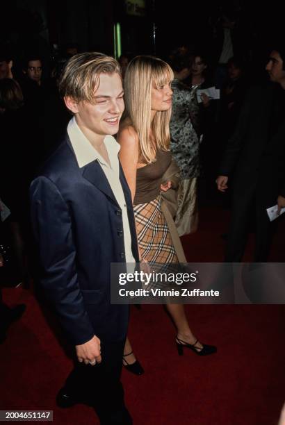 American actor Leonardo DiCaprio, wearing a black suit with a white wide-collar shirt, and American actress and model Kristen Zang, who wears a brown...