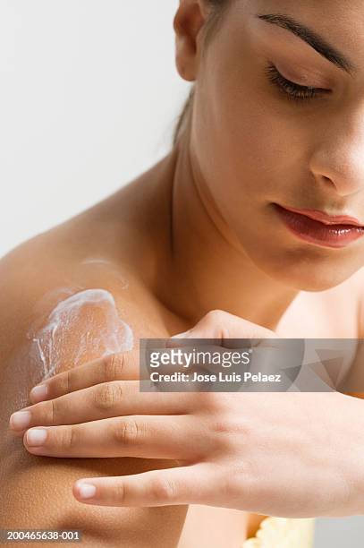 teenage girl (14-16) applying body lotion to shoulder - hand rubbing stockfoto's en -beelden