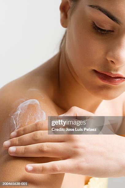 teenage girl (14-16) applying body lotion to shoulder - skin cream stock pictures, royalty-free photos & images