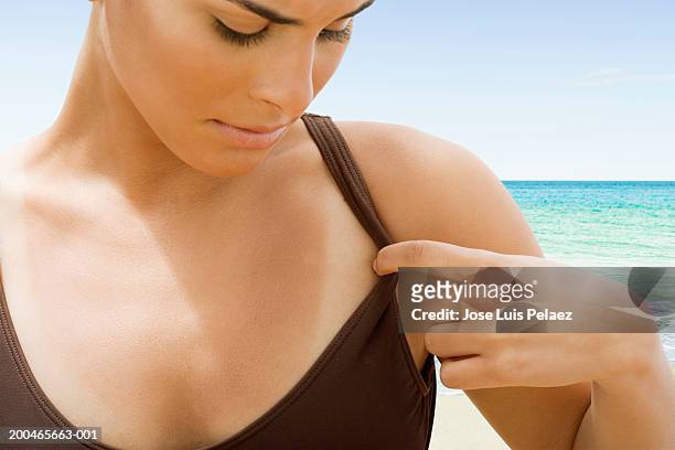 teenage girl (14-16) looking at tan lines at beach - quemado por el sol fotografías e imágenes de stock
