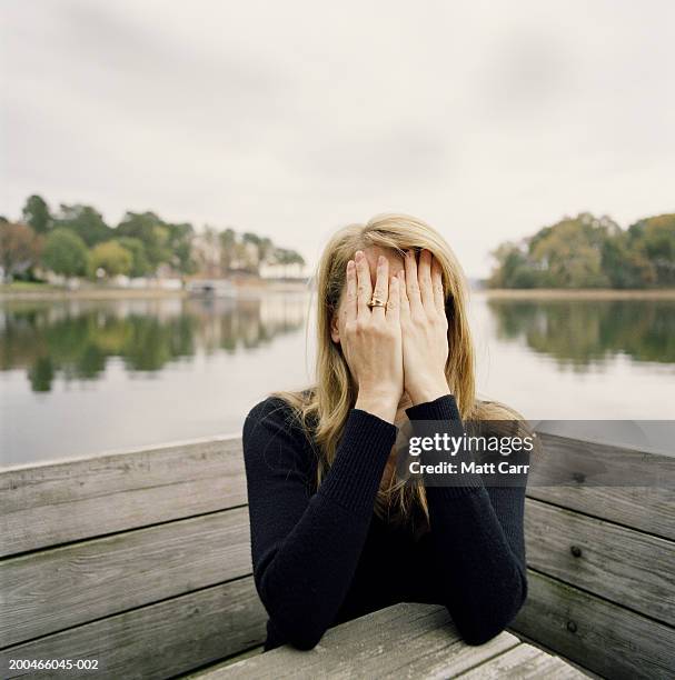 woman covering face, lake in background - awkward stock pictures, royalty-free photos & images