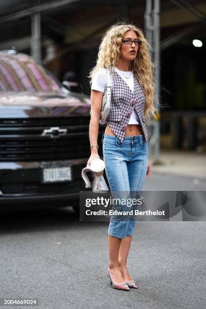 Emili Sindlev wears glasses, a white crop t-shirt, a checkered / checked pattern printed waistcoat with bejeweled / rhinestones buttons, cropped blue...