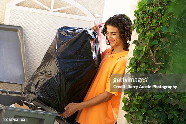 coy (13-15) putting out rubbish, smiling - garbage bag stock pictures, royalty-free photos & images