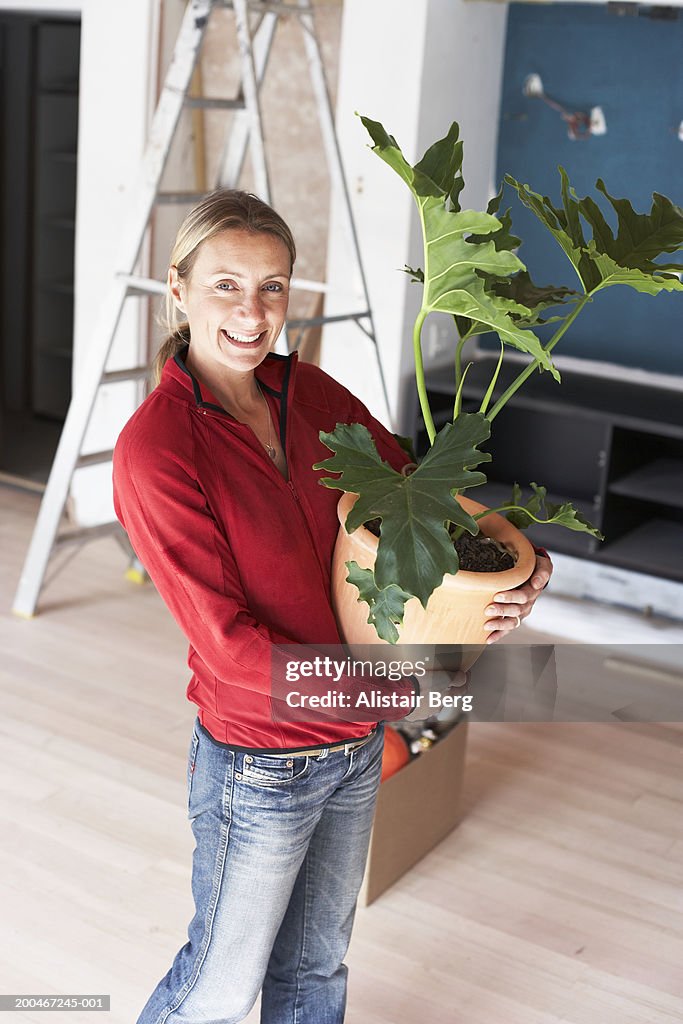 Woman carrying potted plant, smiling, portrait