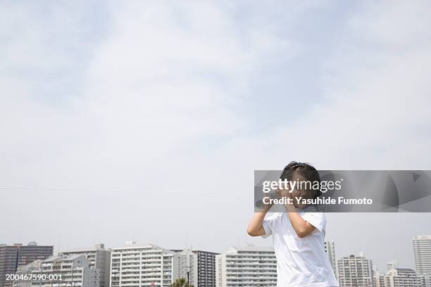 girl (7-9) holding tin can phone to ear, cityscape in background - listening tin can stock pictures, royalty-free photos & images