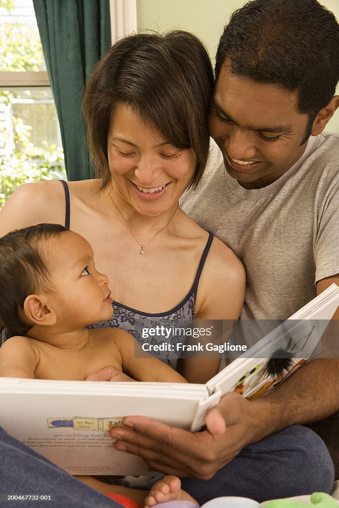 Mother and father reading book to baby boy (9-12 months)