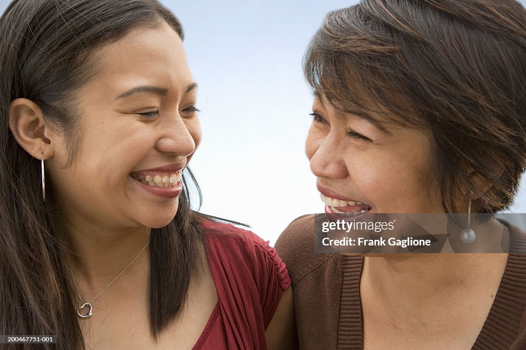 Mother and adult daughter looking at one another, laughing