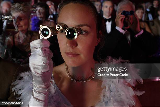 woman in audience using opera glasses - binocolo da teatro foto e immagini stock