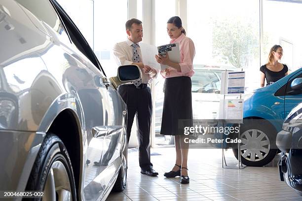 woman talking to auto salesman in showroom - sports car showroom stock pictures, royalty-free photos & images