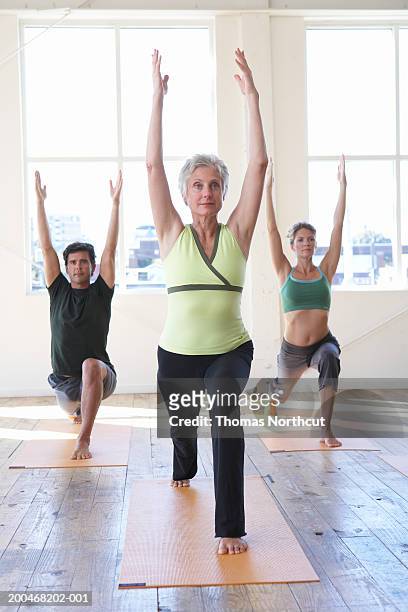 three adults practicing yoga, arms raised - woman straddling man stock pictures, royalty-free photos & images