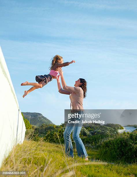 girl (5-7) jumping off wall into mother's arms, outdoors - child arms raised stock pictures, royalty-free photos & images