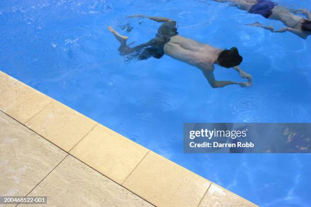 young couple swimming underwater in pool, elevated view - ブレスト ストックフォトと画像