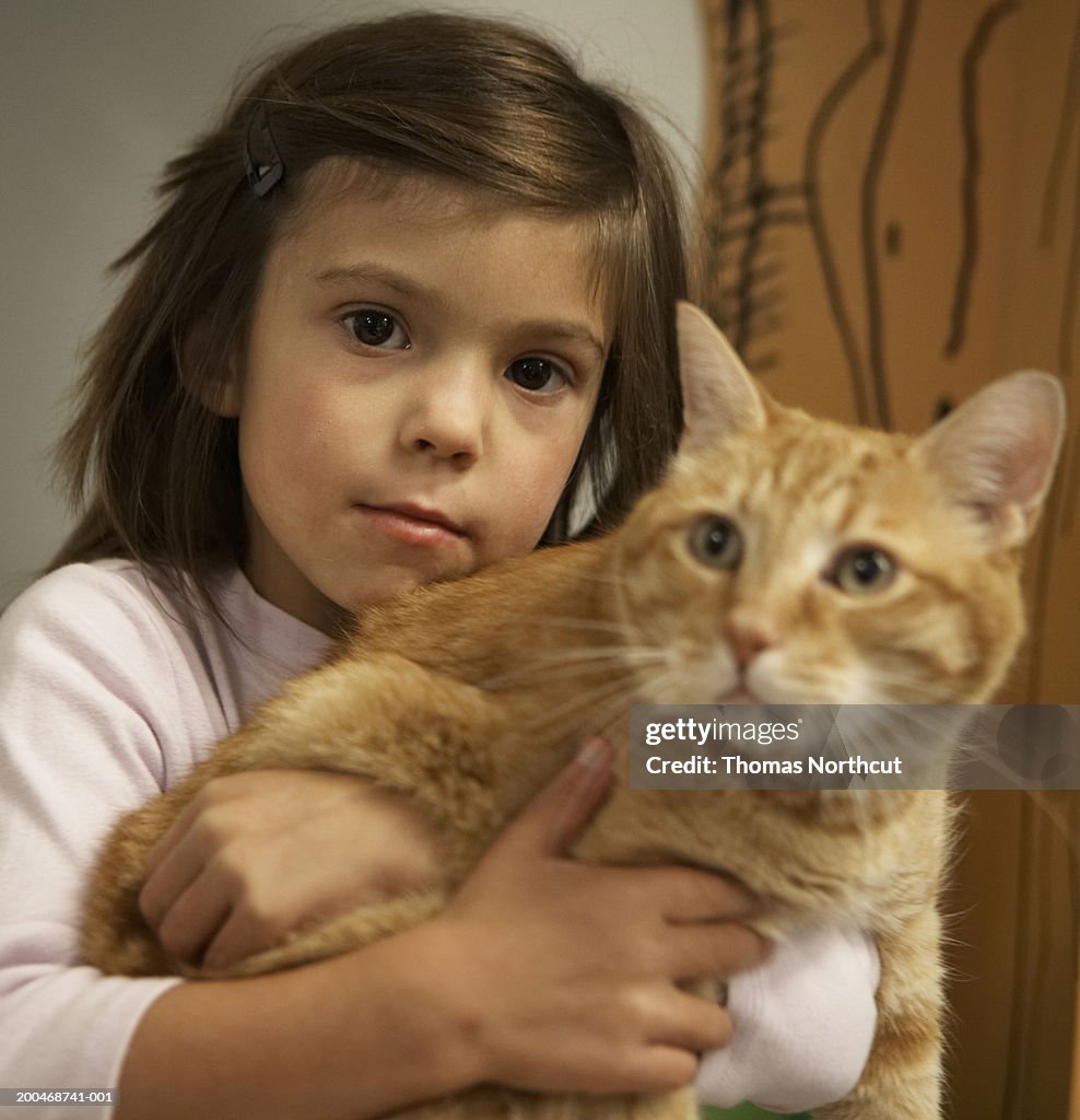 Girl (5-7) holding cat, portrait (focus on girl)