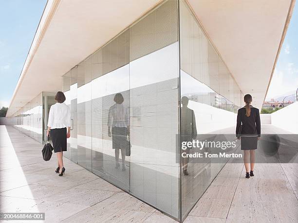 two businesswomen walking either side of building, rear view - triangle day 2 stock-fotos und bilder