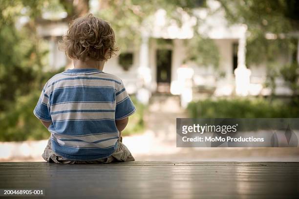 male toddler (21-24 months) sitting on porch, rear view - back porch stockfoto's en -beelden