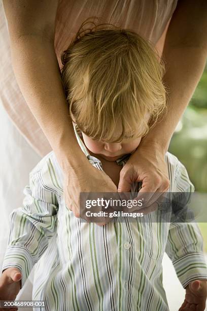 mother buttoning male toddler's (21-24 months) shirt - buttoning shirt stockfoto's en -beelden