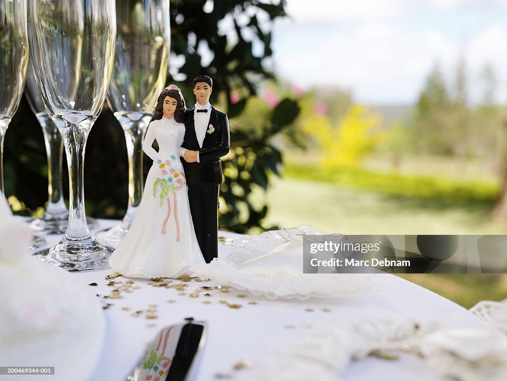 Bride and groom figurine on table by champagne flutes