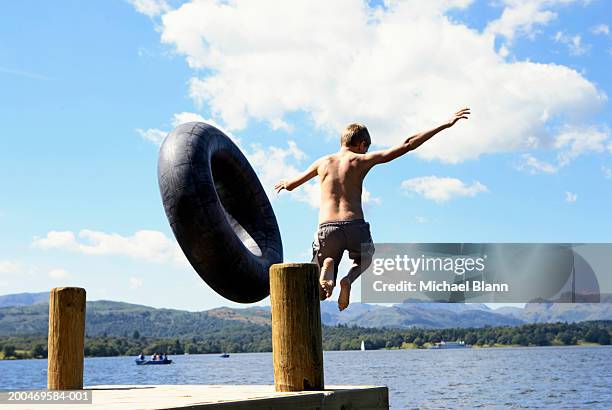 boy (12-14) jumping off jetty into lake, rear view - lago windermere fotografías e imágenes de stock