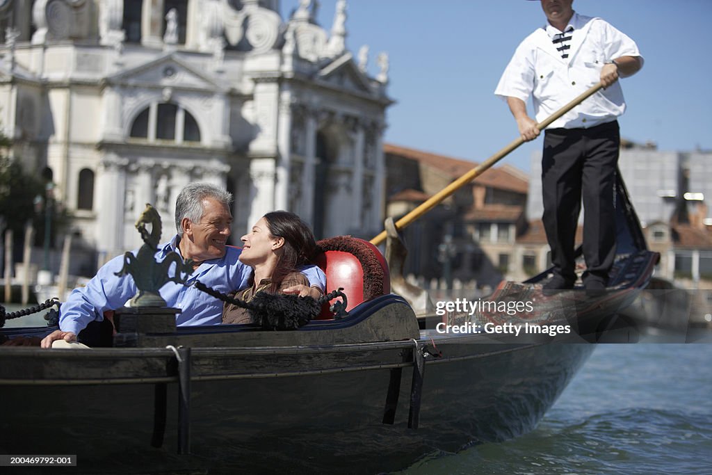 "Italy, Venice, couple riding in godola, smiling at each other"