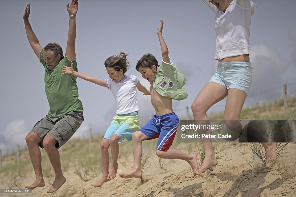 Family jumping down beach dune