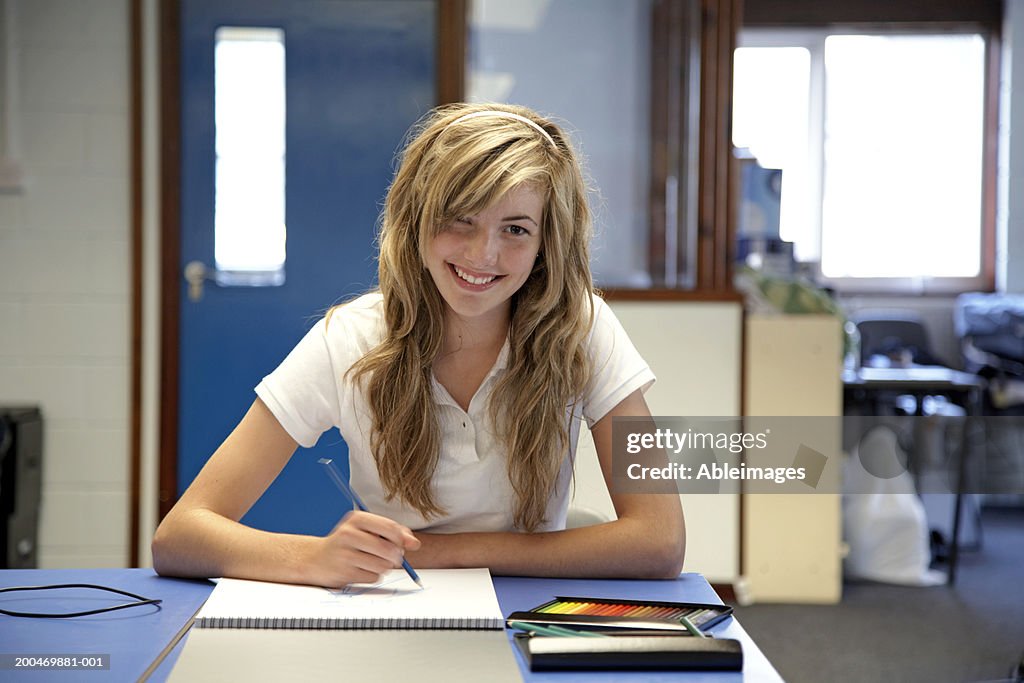 Teenage Girl Sitting At Desk Drawing In Sketchbook Portrait High