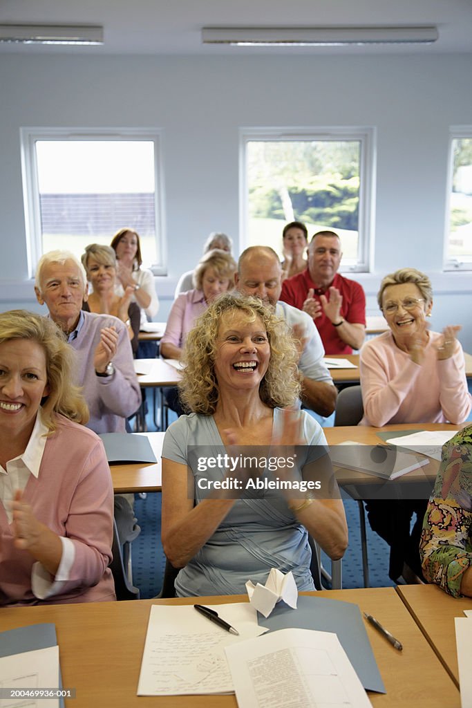 "Mature men and women in classroom, clapping"