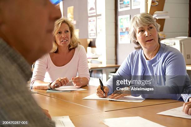 mature men and women gathered around seminar table - adult learning stock pictures, royalty-free photos & images