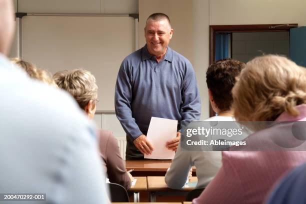 mature men and women in classroom, teacher standing at front - adult education stock pictures, royalty-free photos & images