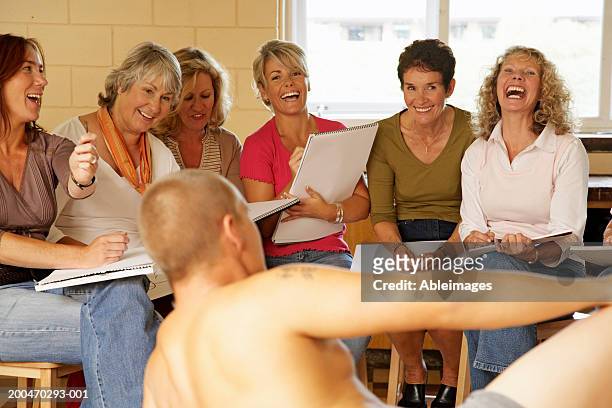 mature women in life drawing class, smiling and laughing at male model - life drawing model stock pictures, royalty-free photos & images
