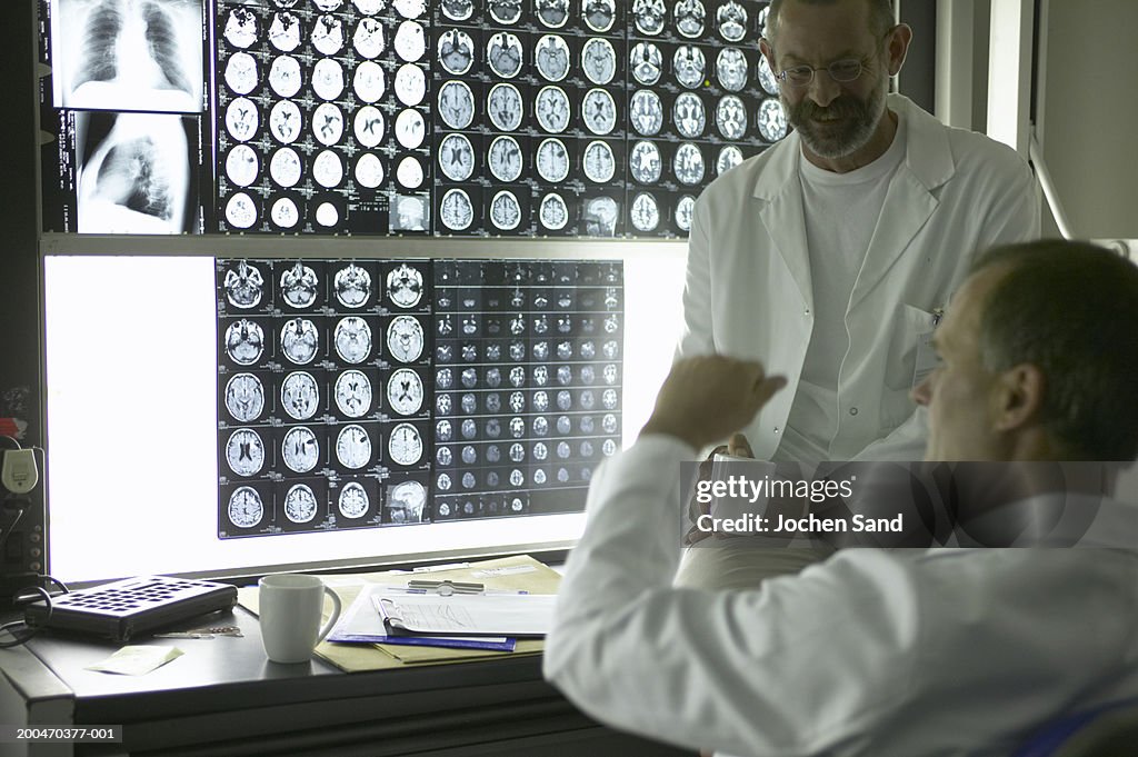 Two male doctors by lightboxes showing X-Rays and MRI scans
