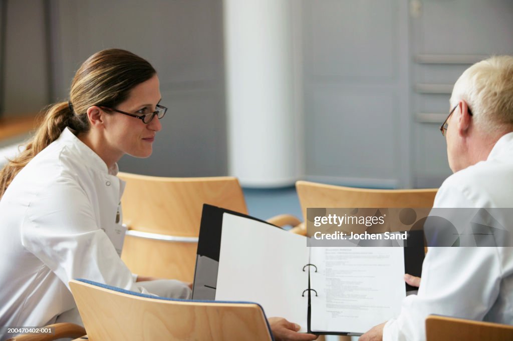 Female doctor showing notes to male colleague