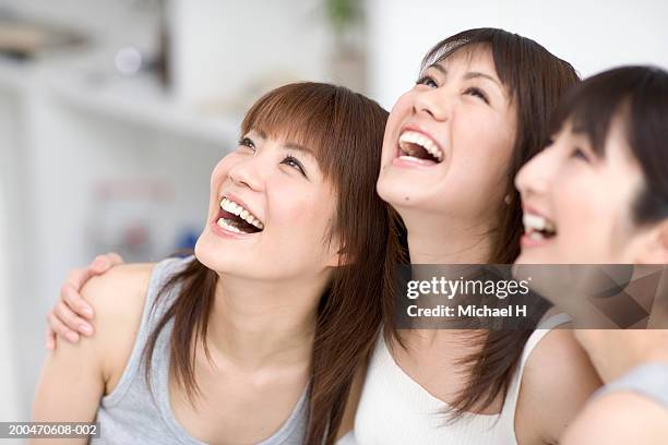 three young women standing side by side, looking up, laughing - tank top ストックフォトと画像