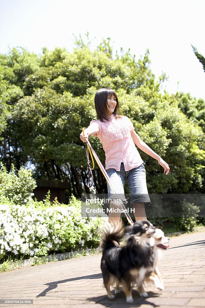 Young woman two dogs on leashes, smiling, looking away