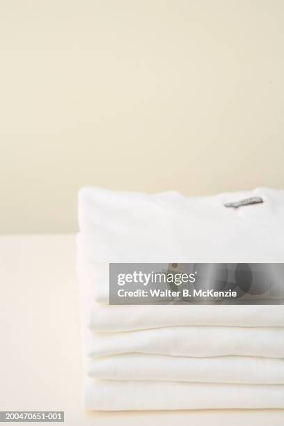 stack of white t-shirts - camisa blanca fotografías e imágenes de stock