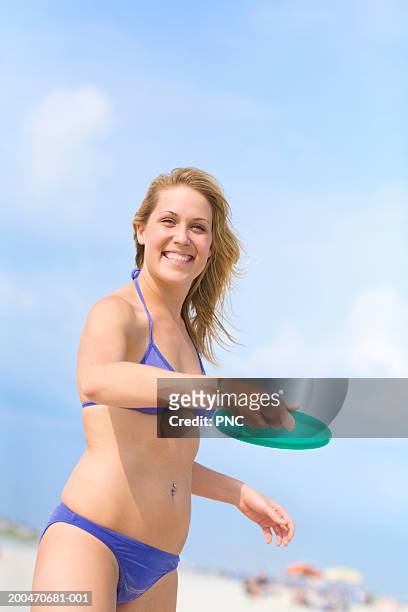 teenage girl (16-18) throwing plastic disc on beach, smiling, portrait - ocean city maryland stock pictures, royalty-free photos & images