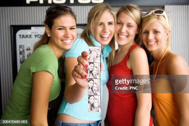four teenage girls (16-18) holding photo booth pictures, portrait - only teenage girls stock pictures, royalty-free photos & images
