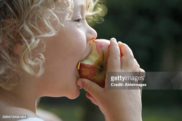 "girl (3-5) biting into apple, profile, close-up" - manger sur le pouce photos et images de collection