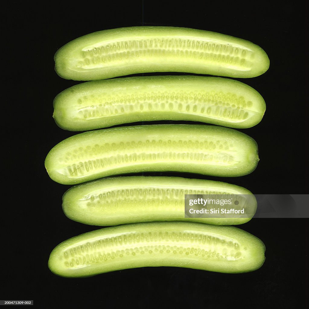 Persian cucumbers cut in half, black background