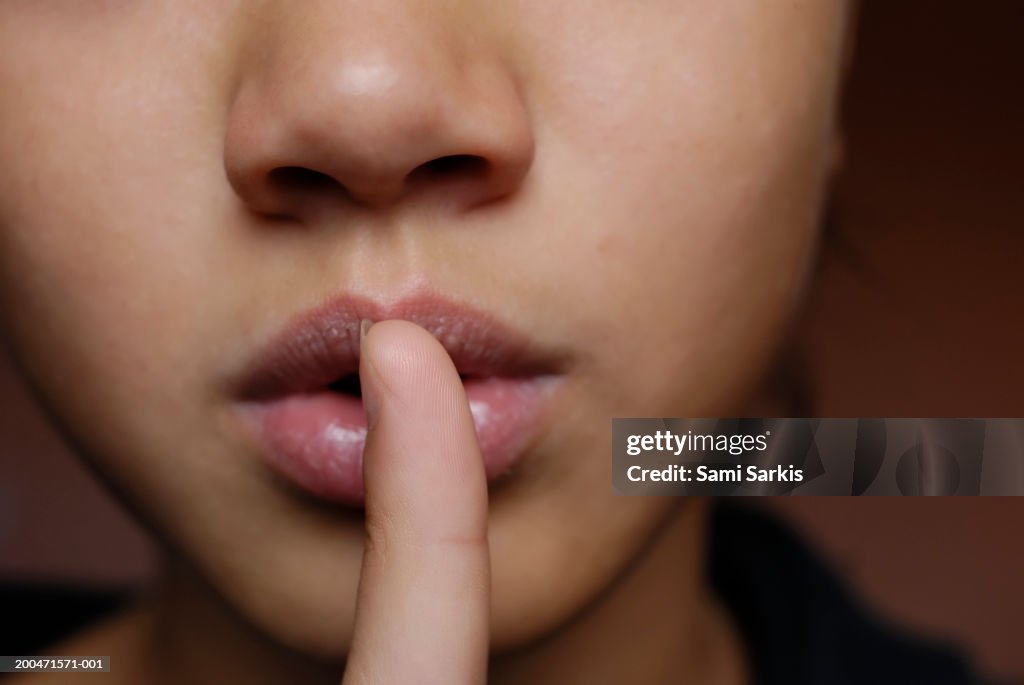 Girl (11-13) finger on lips, close-up
