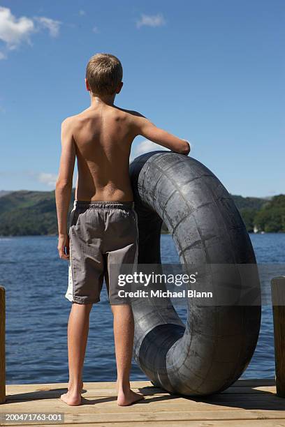 teenage boy (13-15) with inflatable ring on jetty, rear view - boy river looking at camera stock pictures, royalty-free photos & images