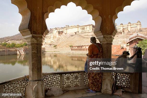 india, rajasthan, woman standing on veranda, amber fort in distance - indian fort stock pictures, royalty-free photos & images