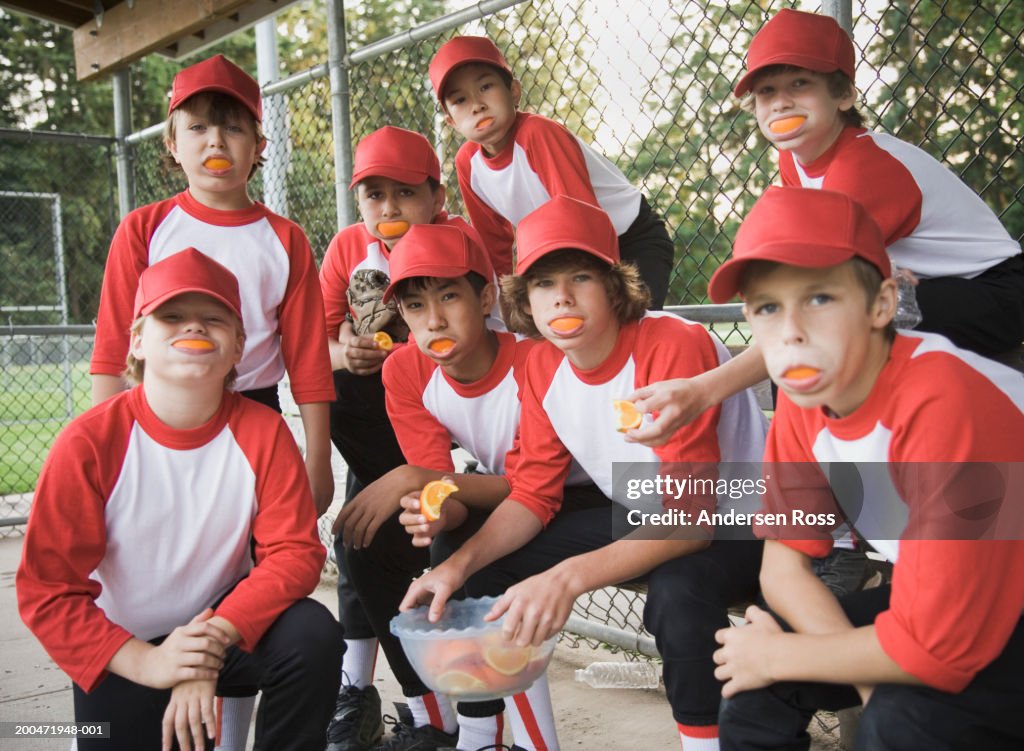 Baseball players (7-14) with orange slices in their mouths, portrait