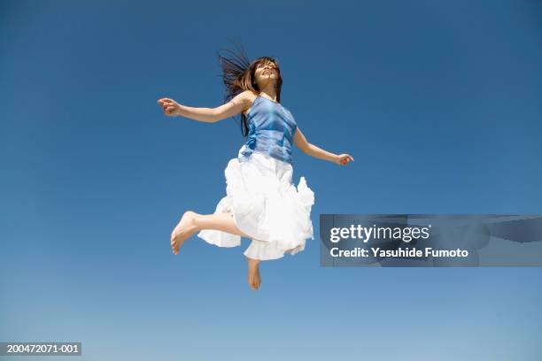 young woman jumping in midair, low angle view - low angle view ストックフォトと画像